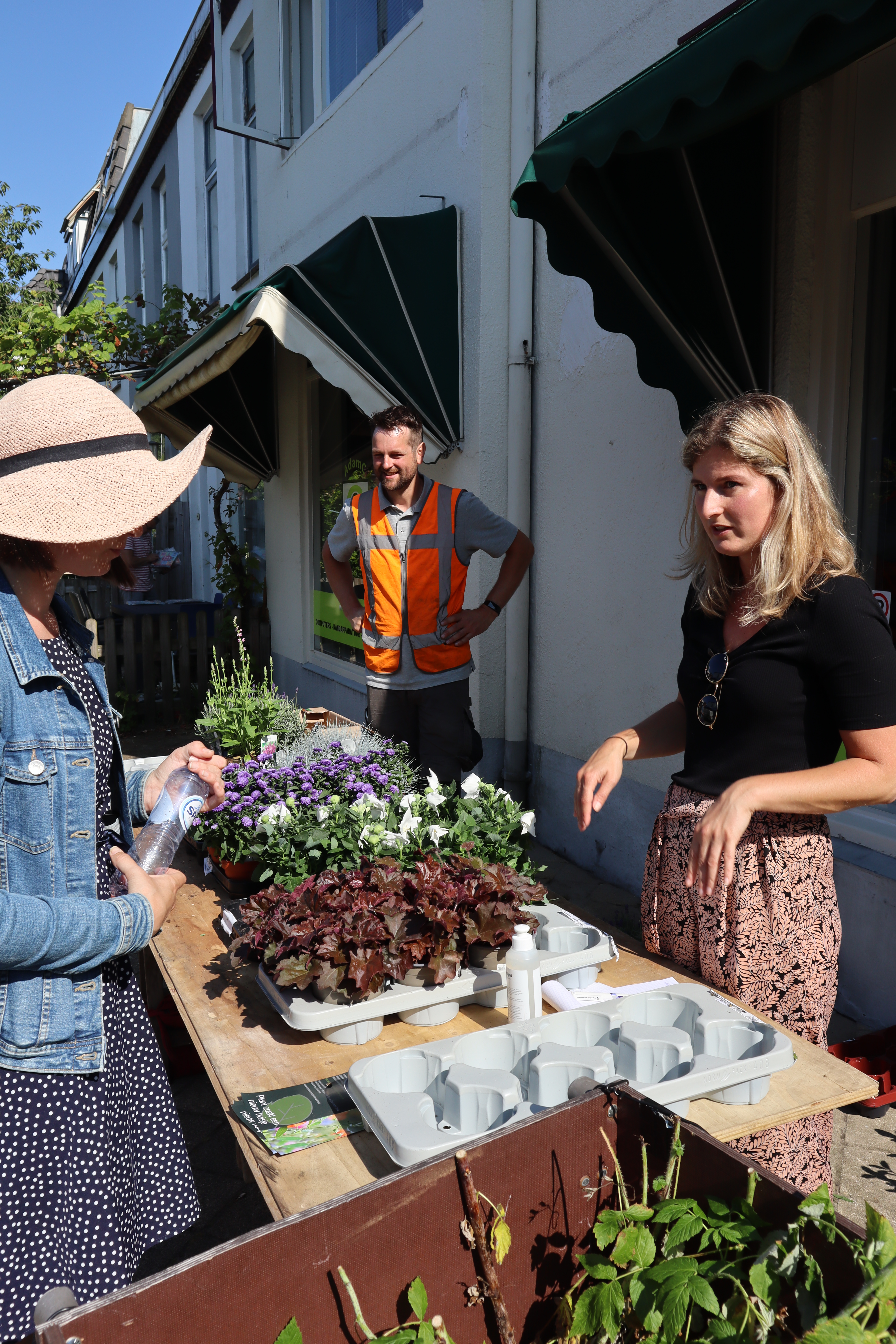 Kraampje met daarop planten en lege plantenbakken waar mensen bij staan