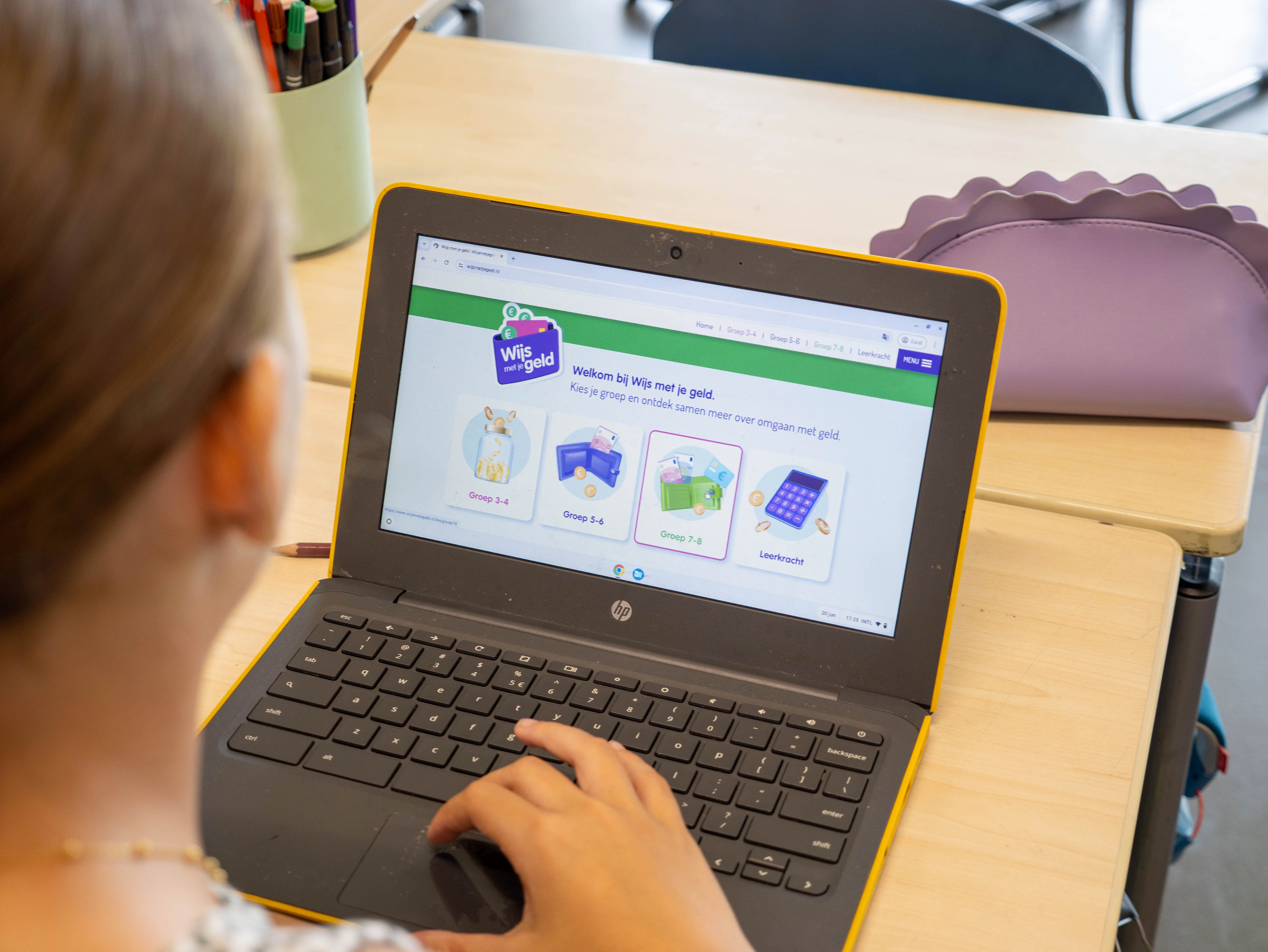 Leerling bekijkt de website van Wijzer in Geldzaken op een laptop met verschillende leeropties zichtbaar.