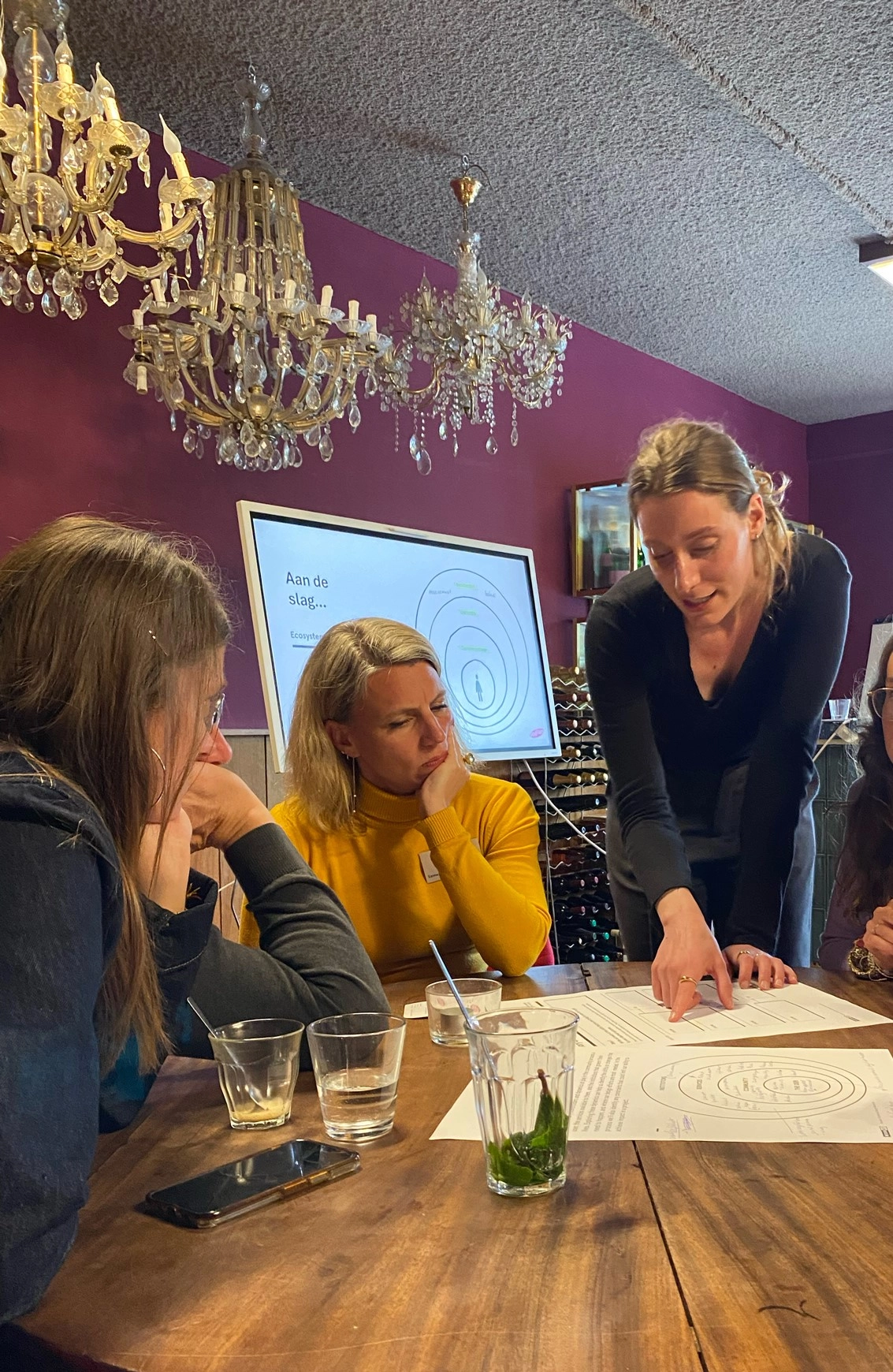 Noeske legt aan een tijdens een workshop Human-Centered Design iets uit aan een tafel met geïnteresseerden.  