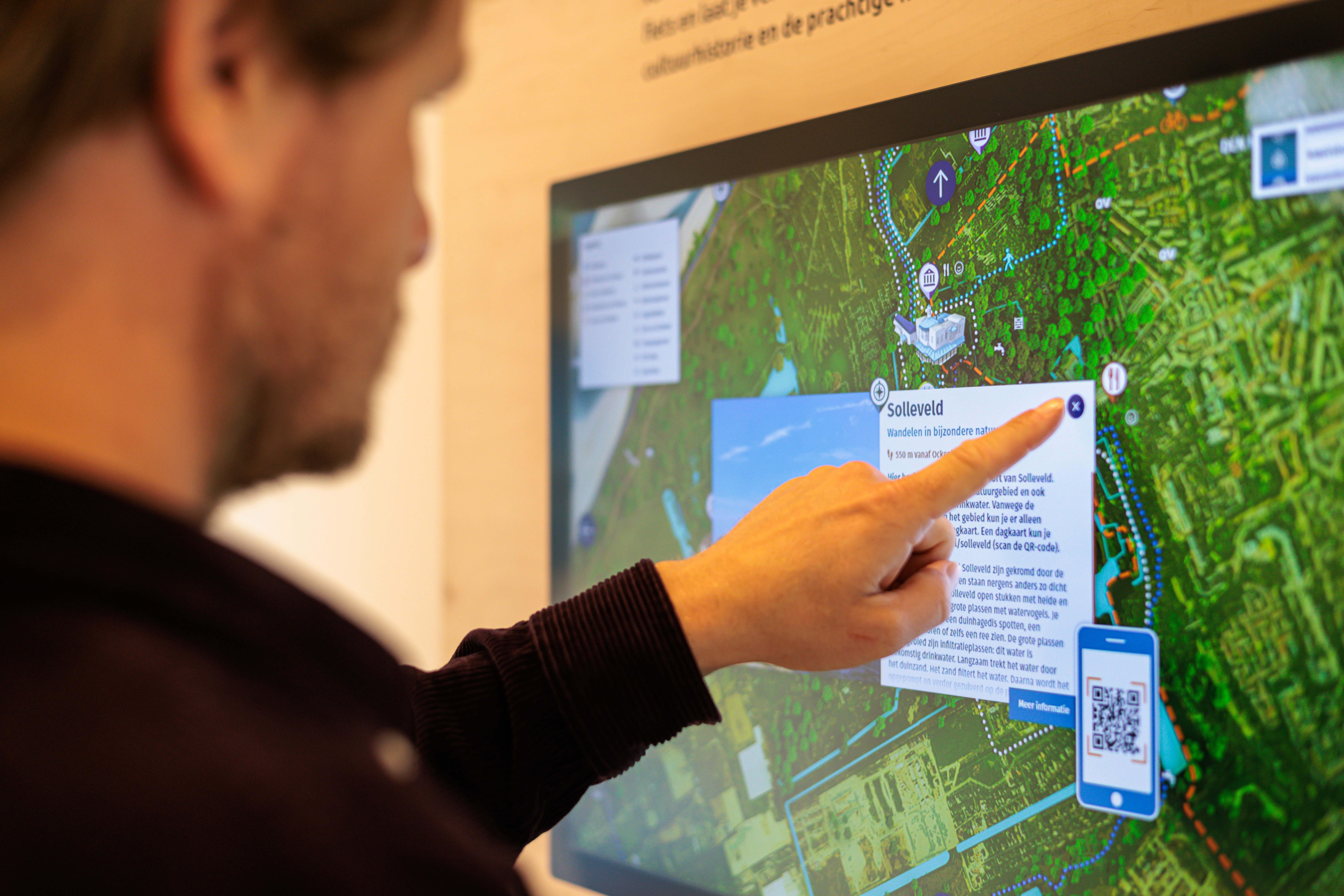 Persoon staat voor een interactief scherm en klikt op een pop-up beeld