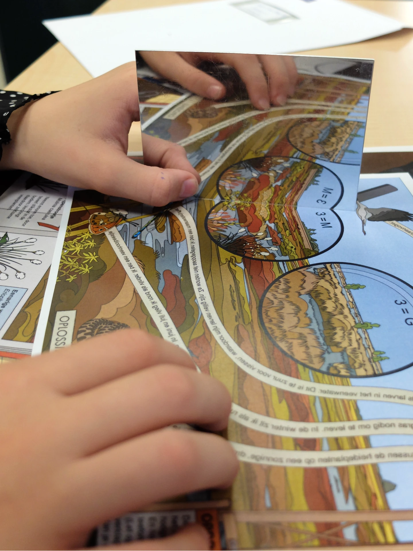 Kind doet een opdracht op tafel met een spiegeltje en probeert zo de letters te lezen
