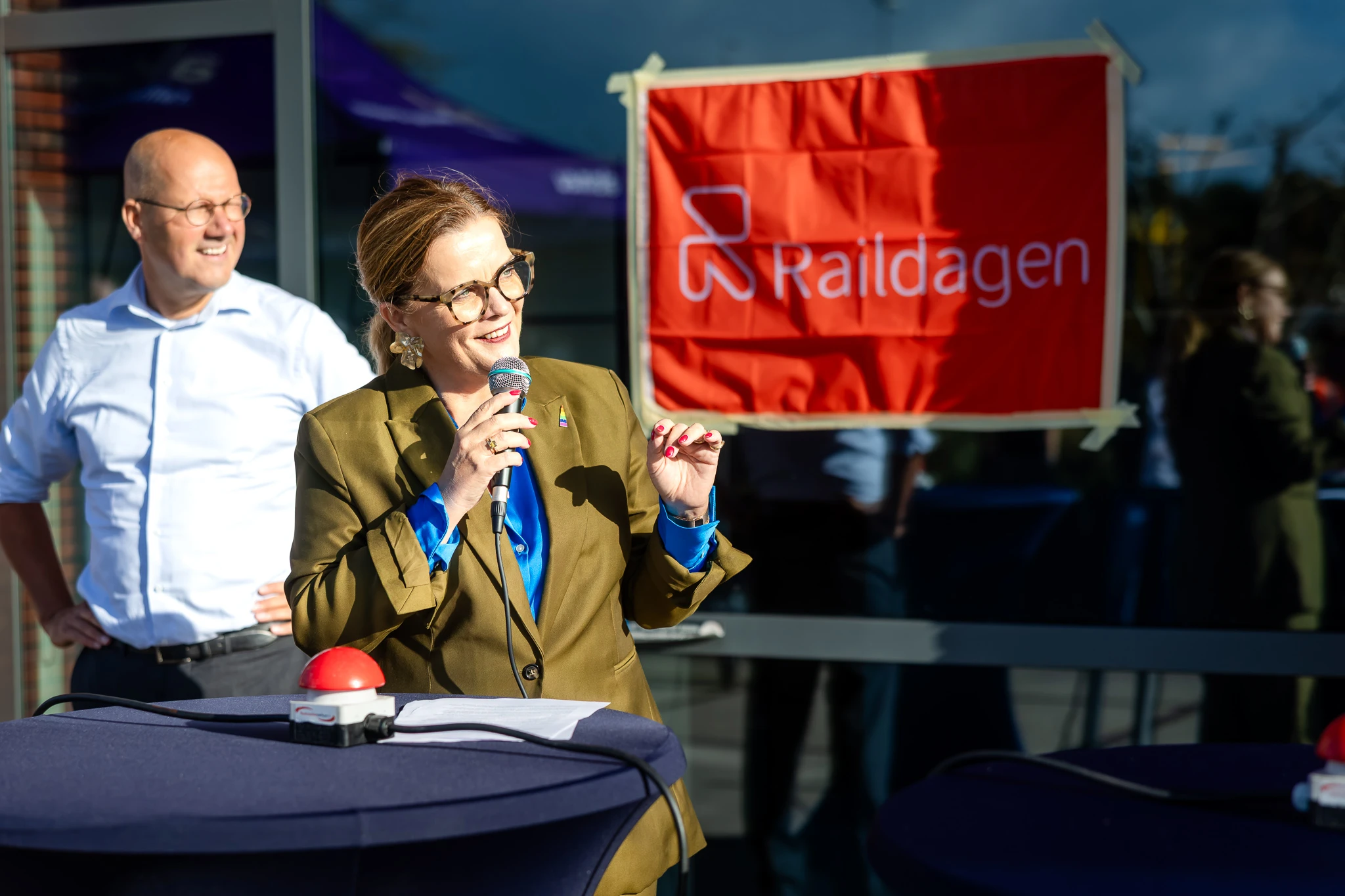 Vrouw staat met microfoon bij het event Raildagen en openingswoordje te doen.