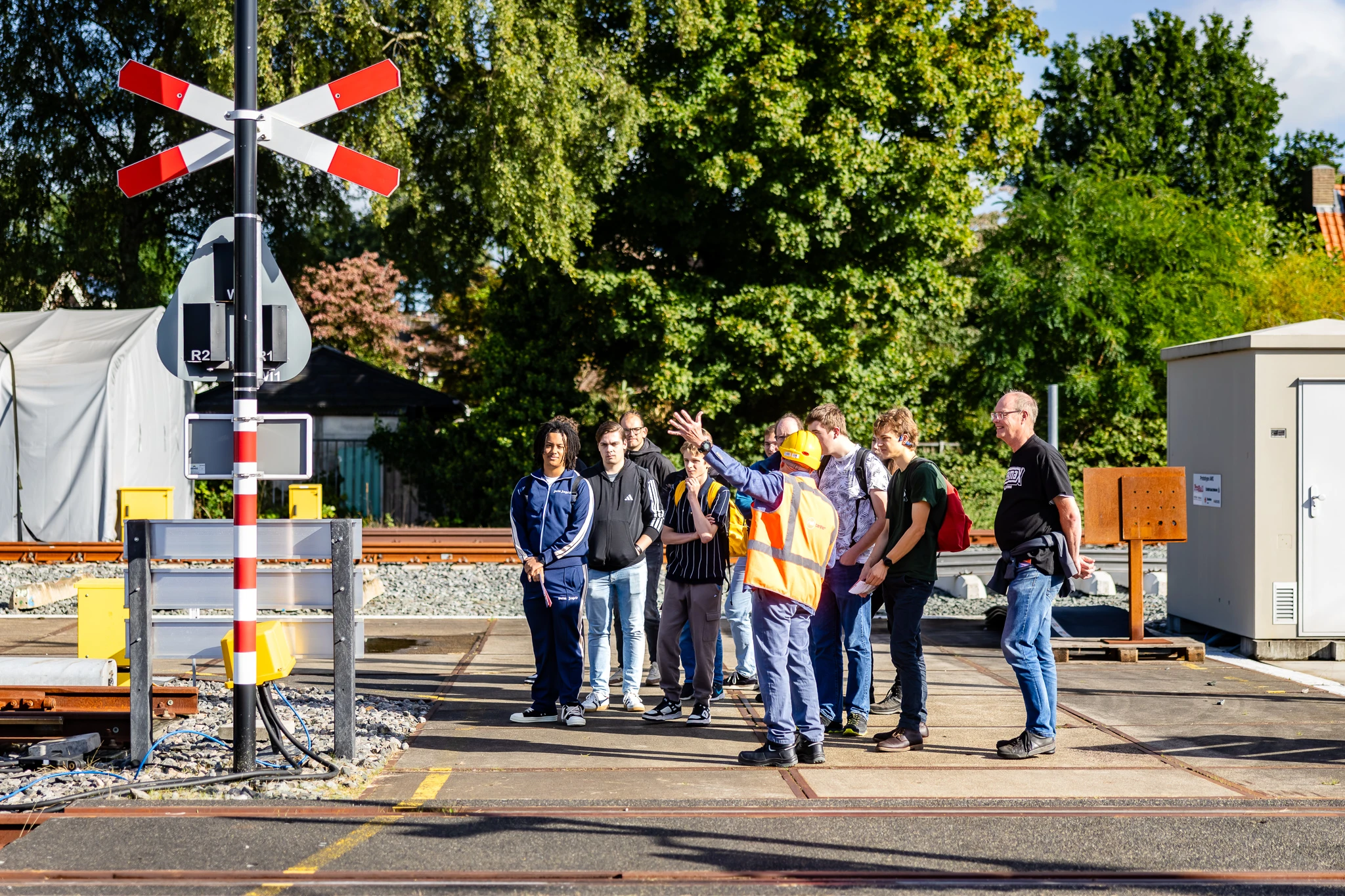 Medewerker Raildagen geeft uitleg aan een groep mensen bij het spoor.